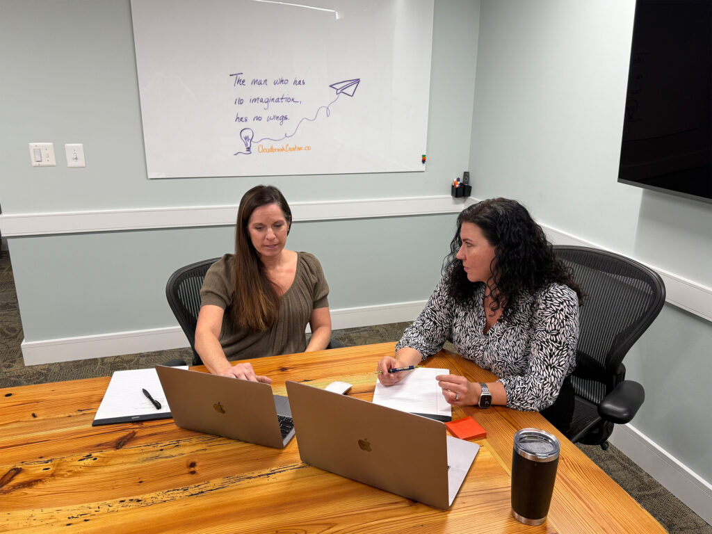 Tracey and Steph sitting at a conference table collaborating on a design project.